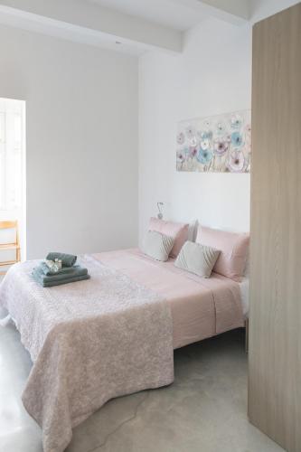 a white bedroom with a large bed with pink sheets at Privilege Suite in Tal-Pietà