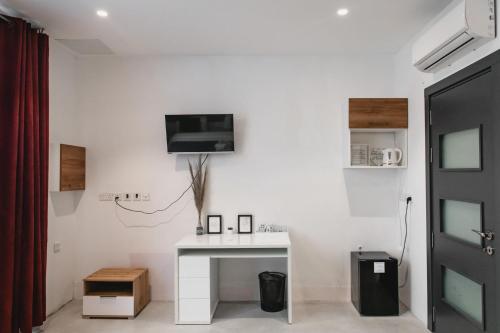 a white room with a desk and a tv on the wall at Privilege Suite in Tal-Pietà