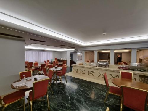 a dining room with tables and chairs and a counter at Savoy Hotel in Piraeus