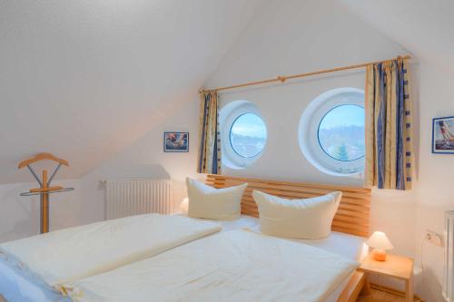 a bedroom with a bed and two windows at Strandhaus Thiessow Whg_ 3 in Thiessow