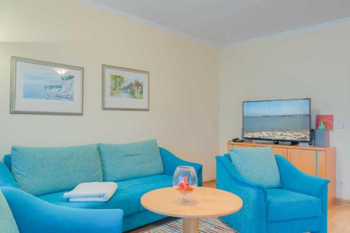 ein Wohnzimmer mit einem blauen Sofa und einem Tisch in der Unterkunft Villa Elfeld 2 Whg. 717 in Binz