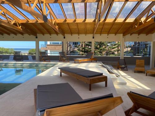 a pavilion with a pool with a bed and chairs at Costanera Mar Hotel & Suites in San Clemente del Tuyú