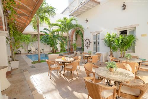 un patio con tavoli, sedie e piscina di Hotel Boutique Don Pepe a Santa Marta