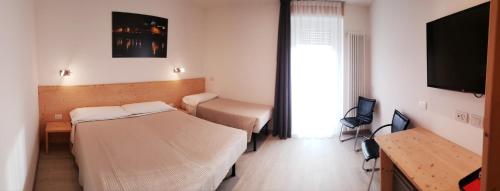 una camera ospedaliera con due letti e una televisione di Hotel Cantaleone a San Michele allʼAdige