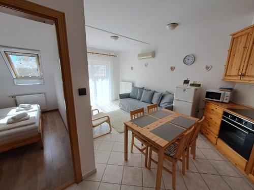 a kitchen and a dining room with a table and a couch at Plázs Apartman Balatonlelle in Balatonlelle