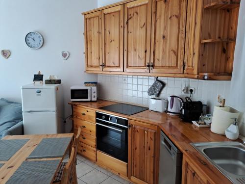 a kitchen with wooden cabinets and a stove top oven at Plázs Apartman Balatonlelle in Balatonlelle