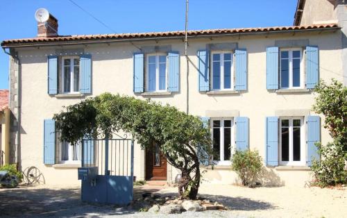 una casa con persianas azules y un árbol delante de ella en Gites79 - Gite des Roses, 30mins Puy du Fou en Saint-Jouin-de-Milly