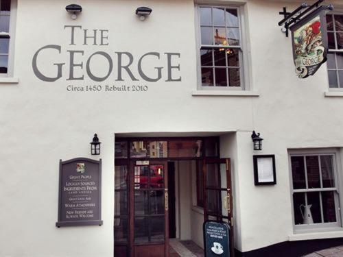 a white building with a sign that reads the greegue at The George Inn in Hatherleigh