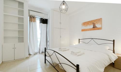 Dormitorio blanco con cama y lámpara colgante en Filis Sunny 80sqm apt in Viktoria, en Atenas