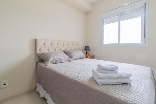 a white bedroom with a bed with towels on it at My Home Studio - GRU in Guarulhos