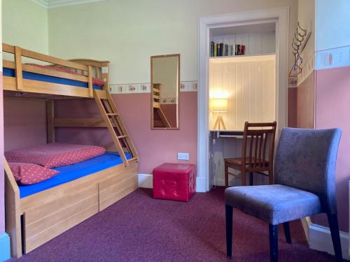 a bedroom with bunk beds and a chair and a mirror at Great Glen Hostel in Spean Bridge