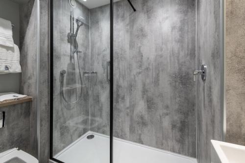 a shower with a glass door in a bathroom at Royal National Hotel in London