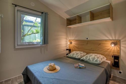une chambre avec un lit avec un chapeau dessus dans l'établissement Camping du Lac de Grolejac, à Groléjac