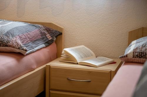 a book on a night stand next to a bed at Haus Avalanche in Saas-Fee