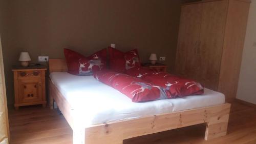a bed with red pillows on it in a room at Loretz Luzia in Silbertal