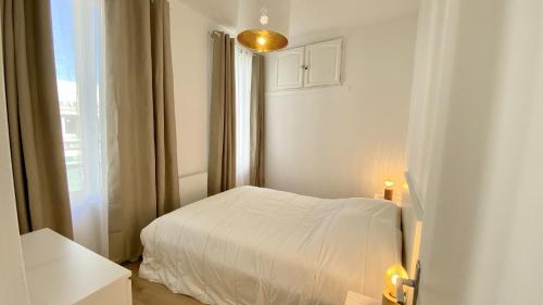 une chambre blanche avec un lit et une fenêtre dans l'établissement L'escapade, au Crotoy