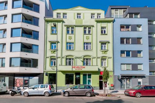 a green building with cars parked in front of it at Revelton Studios Prague in Prague