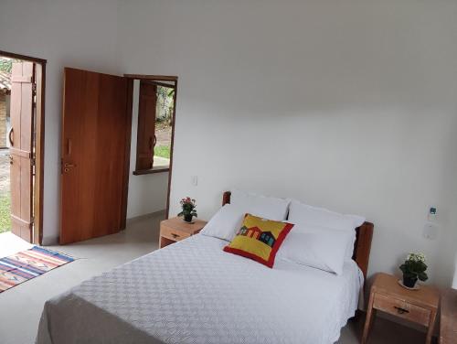 a bedroom with a bed with white sheets and pillows at Casa do Artista in Trancoso