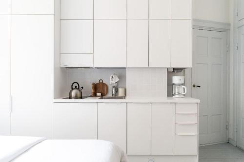 a white kitchen with white walls and white cabinets at Small studio with spacious bathroom in Ullanlinna in Helsinki