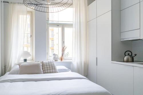 a white bedroom with a bed and a window at Small studio with spacious bathroom in Ullanlinna in Helsinki