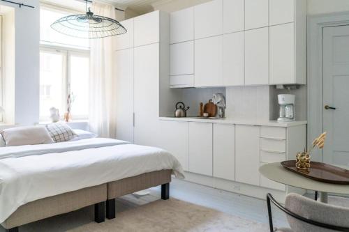 a white bedroom with a bed and a table at Small studio with spacious bathroom in Ullanlinna in Helsinki