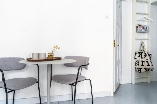 a table and chairs in a room with a white wall at Small studio with spacious bathroom in Ullanlinna in Helsinki