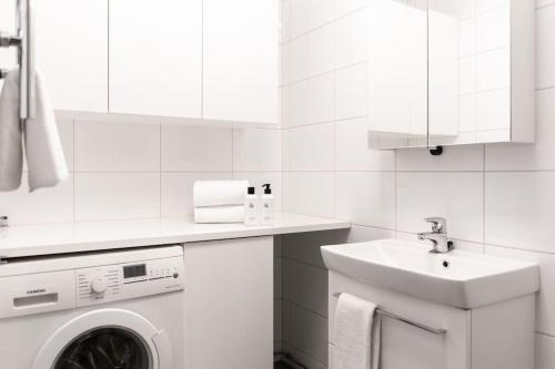 a white bathroom with a washing machine and a sink at Small studio with spacious bathroom in Ullanlinna in Helsinki