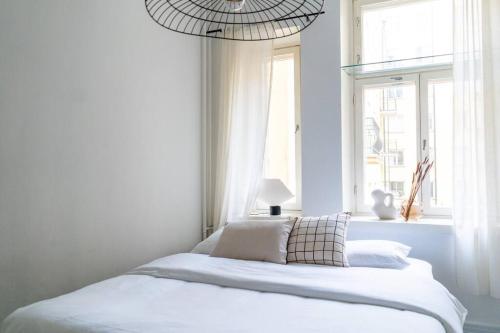 a bedroom with a bed with white sheets and a window at Small studio with spacious bathroom in Ullanlinna in Helsinki