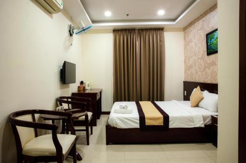 una camera d'albergo con letto, scrivania e sedie di LUXURY HOTEL HẬU GIANG ad Ho Chi Minh
