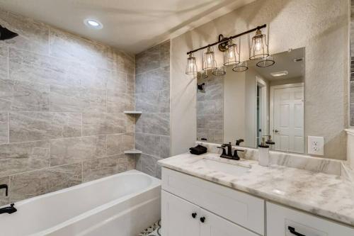 a bathroom with a sink and a tub and a mirror at NEW 4 BDRM Home off St Mary’s Mins To Pearl/River! in San Antonio