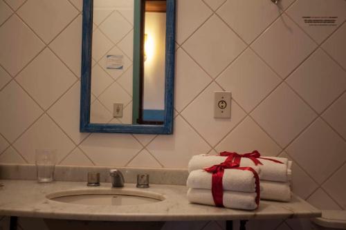 a bathroom sink with towels and a gift on it at Pousada Nascentes da Fortaleza, antiga Água Azul in São Sebastião do Paraíso