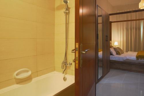 La salle de bains est pourvue d'une baignoire et d'un lit. dans l'établissement Calm&Cozy1BR- Dubai Silicon Oasis-15min-Dxb airpt, à Dubaï