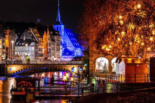 a city lit up at night with a bridge and buildings at Hotel Suisse in Strasbourg