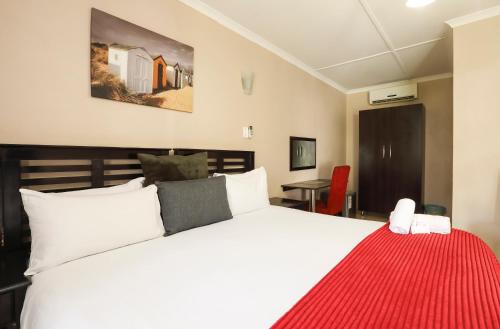 Nongoma Lodge & Inn CC في Nongoma: غرفة نوم بسرير ابيض وبطانية حمراء