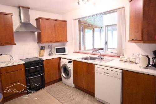 a kitchen with a sink and a washing machine at Hill View Cottage - near Aviemore in Aviemore