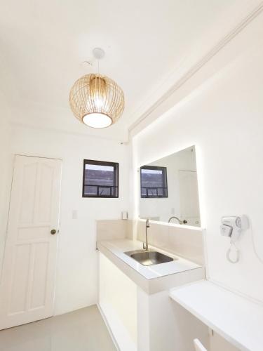 a white bathroom with a sink and a mirror at NomadsMNL Airport Hostel in Manila