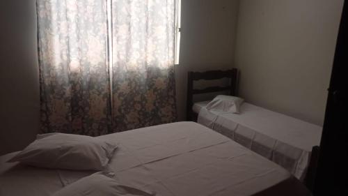 2 Betten in einem kleinen Zimmer mit Fenster in der Unterkunft Pousada Nova in Montes Claros