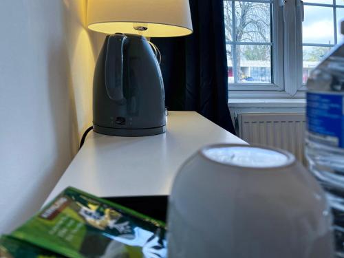 a lamp sitting on top of a table next to a table with aether at Maberic Housing in Cranford