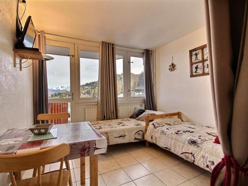 - une chambre avec 2 lits, une table, une table et des chaises dans l'établissement Studio rénové au pied des pistes avec balcon, idéal pour 2 personnes - FR-1-455-117, à La Plagne