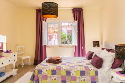 a bedroom with a bed with purple curtains and a window at Casa Júlio Henriques in Caldas da Rainha