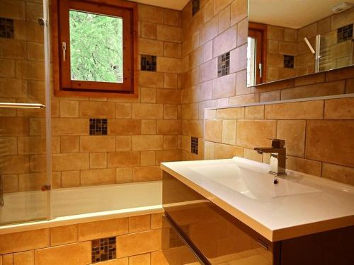 La salle de bains est pourvue d'un lavabo, d'une baignoire et d'une fenêtre. dans l'établissement Chalet rénové pour 10 avec jacuzzi, cheminée et WiFi aux pieds des pistes - FR-1-455-155, à La Plagne