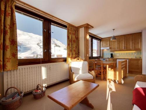 un salon avec une table et une cuisine enneigée dans l'établissement Grand appartement pour 6 au pied des pistes, lumineux avec balcon - FR-1-455-165, à La Plagne