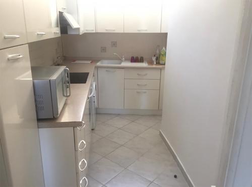 une cuisine avec des armoires blanches et un micro-ondes dans l'établissement calme et tranquillité et un soupir, à Menton