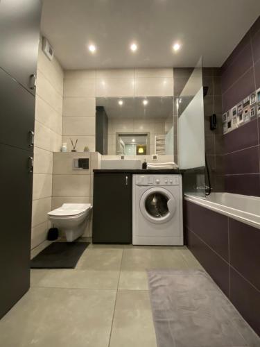 a bathroom with a washing machine and a toilet at Apartament Majakowskiego DG in Dąbrowa Górnicza