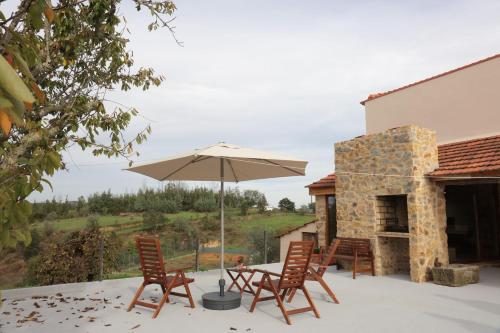 a patio with a table and chairs and an umbrella at Vale das Maias - Casa de Campo in Laborins