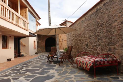 a patio with a table and an umbrella at Vale das Maias - Casa de Campo in Laborins