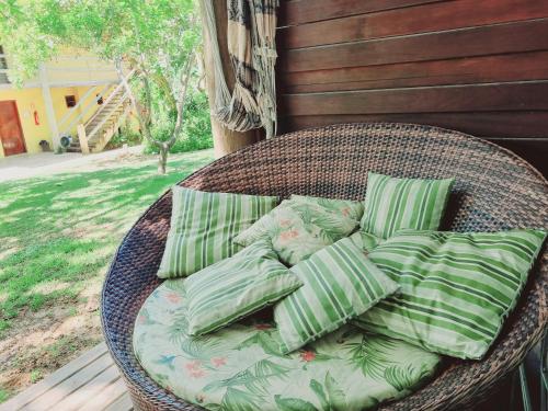 uma cesta de vime com almofadas verdes num alpendre em Villas do Pratagy Maceió em Maceió