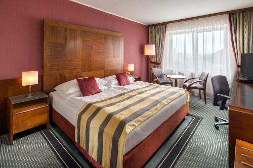 a hotel room with a bed and a table and chairs at Quality Hotel Brno Exhibition Centre in Brno