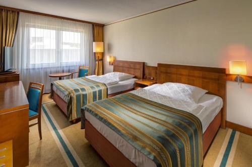 a hotel room with two beds and a table at Quality Hotel Brno Exhibition Centre in Brno
