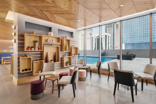 a lobby with chairs and tables and a pool at Wyndham Doha West Bay in Doha